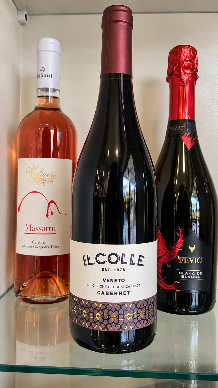 Tre bottiglie di vino su mensola di vetro